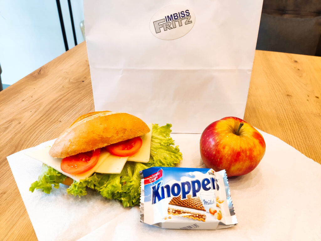 Frühstückstüte von Klein Catering mit belegtem Brötchen, Apfel und Knoppers – perfekt für unterwegs, Ausflüge oder Meetings im Kreis Herford. Klein S Frühstückstüten