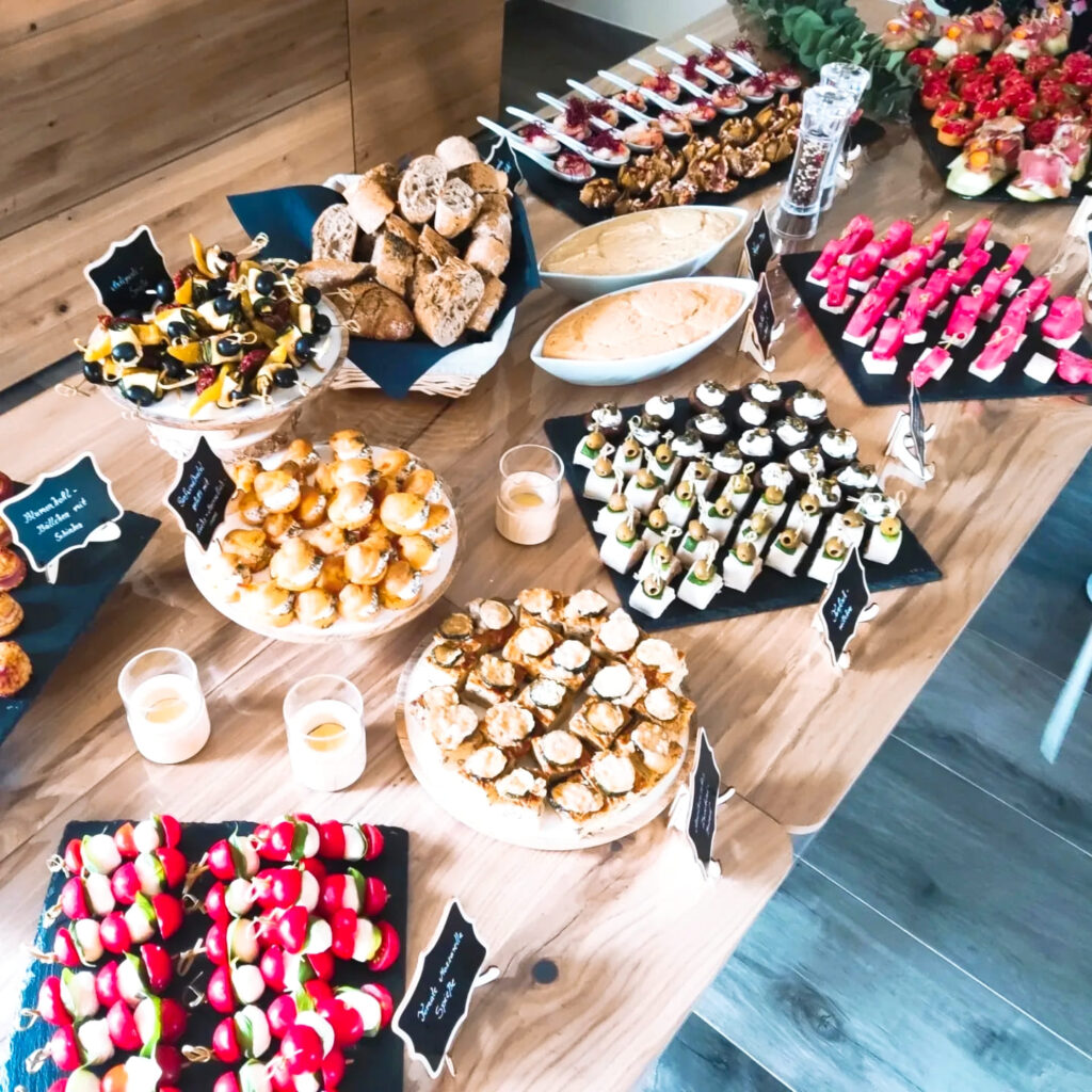 Ein liebevoll angerichtetes Fingerfood-Buffet von Klein Catering mit vielfältigen Häppchen, frischen Brotsorten, Dips und bunten Spießen, ideal für Events